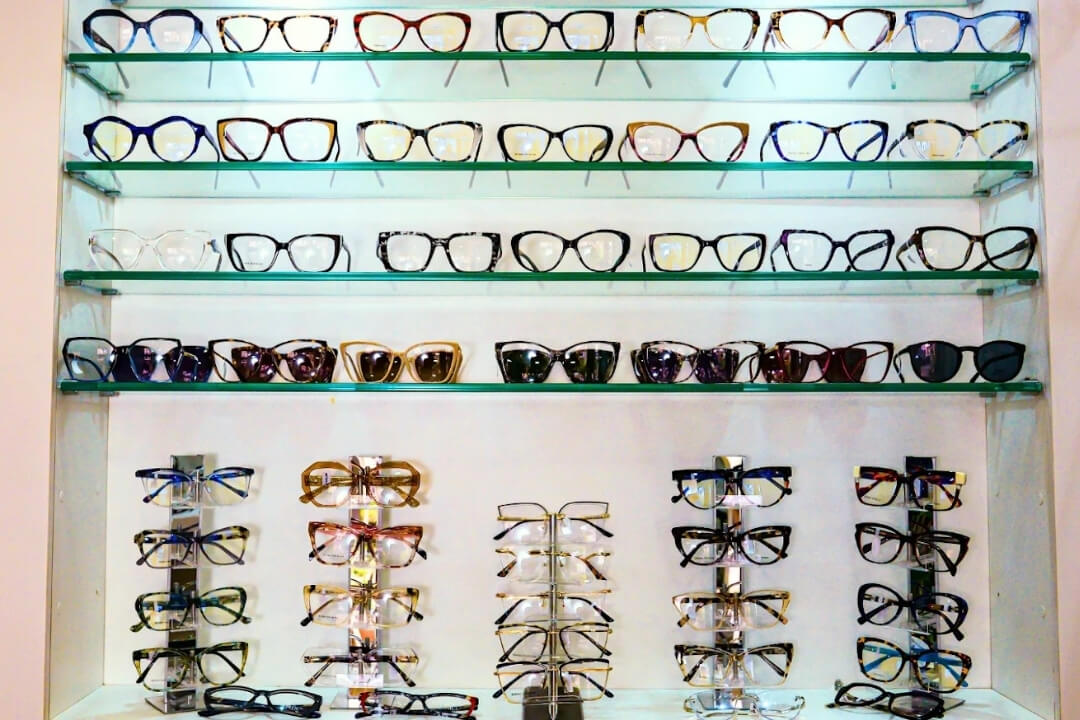 Expositor de parede iluminado com grande variedade de armações de óculos de grau e solares.