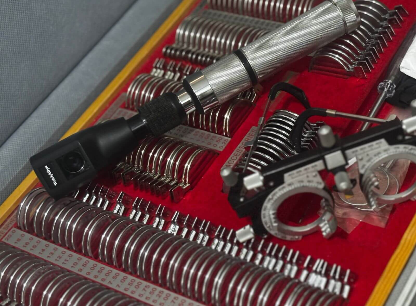 Detalhe de instrumentos de optometria: retinoscópio e estojo de lentes de teste profissionais.